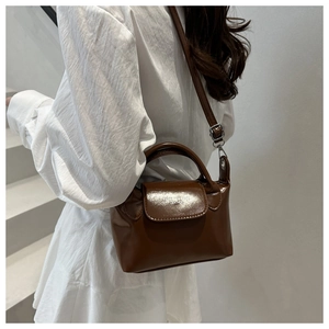Détail du sac bandoulière en cuir brillant marron avec inscription de mode classique