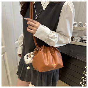 Detail of caramel brown ruched crossbody cloud bag with cute white plush sheep keychain