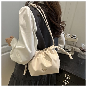 Close-up of pleated beige drawstring bucket bag with Fashion & Bags leather logo detail
