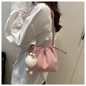 Detail of pink pleated leather crossbody bag with drawstring closure and plush pendant