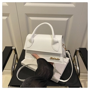 Gros plan du mini sac blanc en cuir texturé avec logo doré posé sur une chaise chic
