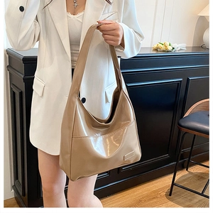 Detail view of khaki patent leather tote bag with rectangular tag and minimalist design