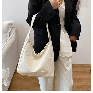 Minimalist cream patent leather tote bag styled on model with black blazer and white pants