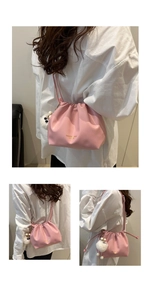 Detail of pink pleated drawstring bucket bag with soft leather texture and plush charm