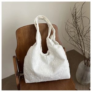 Detail showing white floral embroidered fabric and texture of the large shoulder tote bag