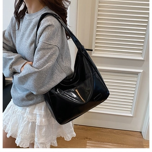 Detailed view of large black patent leather hobo bag with high gloss finish and wide strap