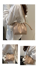Detail of apricot drawstring bucket bag with gold lettering and white fur ball charm