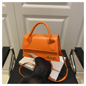 Détail d'un sac à main en cuir orange vif avec un logo signature en métal doré