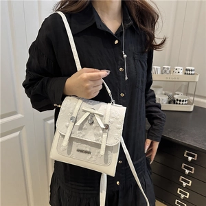 Sac à bandoulière blanc avec motif fleuri en relief et nœud porté par mannequin