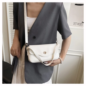 Close-up of minimalist white shoulder bag with golden oval twist-lock on a grey blazer