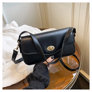 Detailed close-up of the black synthetic leather bag and its golden oval twist lock
