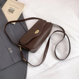Detailed view of deep brown leather crossbody bag with elegant gold oval twist lock