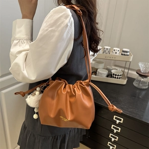 Brown leather ruched cloud bag with plush pompom charm and adjustable strap for women