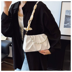 Détail d'un sac froncé blanc avec chaîne en perles et bandoulière en soie à nœud