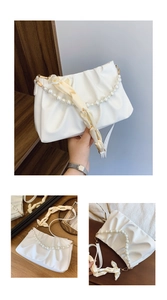Detail of white pleated handbag with elegant pearl chain and cream satin ribbon