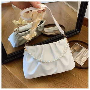 Close-up of white pleated cloud bag featuring glossy PU leather and large pearl chain detail