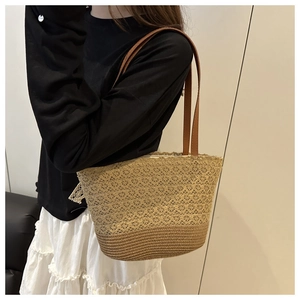Detail of handwoven straw tote bag with delicate lace cutout patterns and brown leather straps