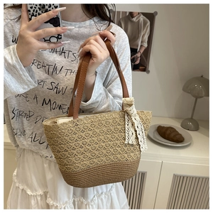 Detail of hollow woven straw tote bag with brown leather handles and lace bow accent