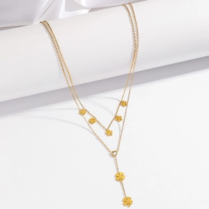 Macro detail of gold-plated layered necklace with clover charms and zircon heart pendant