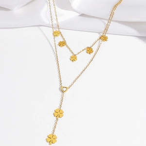 Close-up of golden double-layer clover necklace with heart pendant and sparkling zircon