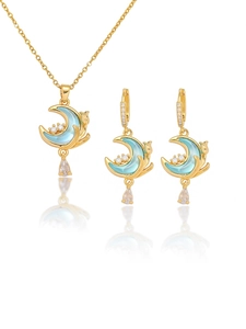 Detailed close-up of gold moon necklace and cat silhouette earrings set with blue stones