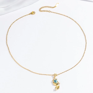 Gold tulip necklace with blue heart gemstone and star detail on white silk background