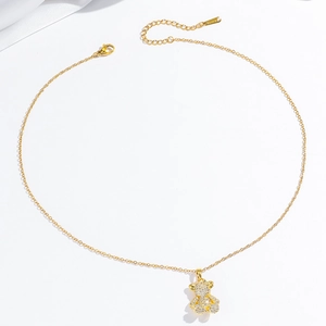 Collier élégant doré avec un pendentif ours serti de zircons sur fond de soie blanche