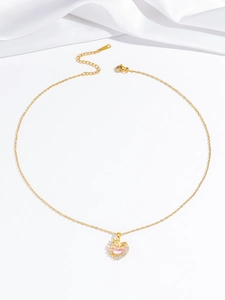 Detail of gold necklace with pink heart pendant, wing accents, and lobster clasp closure