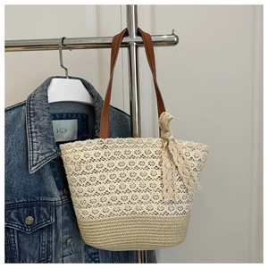 Detail view of woven lace tote bag with brown leather straps and beige bow decoration