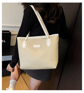Detail of off-white woven tote bag with a fine leather texture and slim shoulder strap