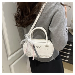 Detail of white faux leather bowling bag with lace bows and heart-shaped laser cut trim