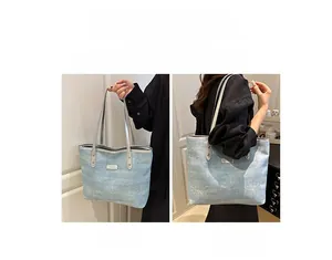 Detail view of light blue denim tote bag showing handheld and shoulder carrying options