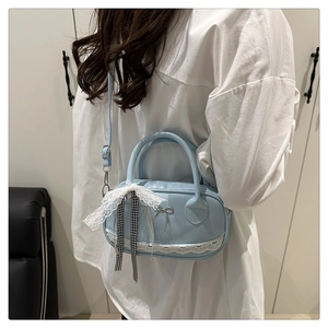 Detail of light blue lace crossbody bag with metal bow and checkered ribbon strap