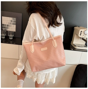 Detailed macro view of pink woven texture tote bag featuring a leather logo patch