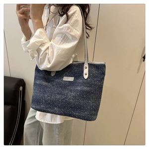 Close-up of a navy denim tote bag with white polka dots and silver fashion metal plate
