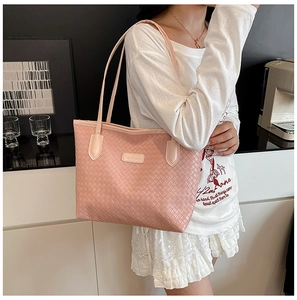 Pink woven leather tote bag with long straps shown in a modern lifestyle setting