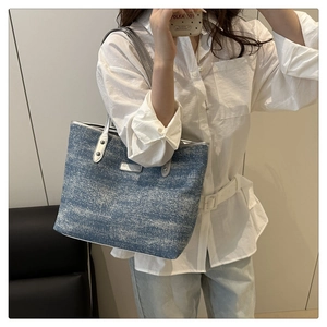 Close-up of blue denim tote bag with silver leather trim and metal fashion nameplate