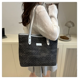 Detail of silver metallic leather straps and logo plaque on a black sequined tote bag