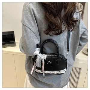 Rear view of a model wearing a black shell bag with lace trim and bow charm