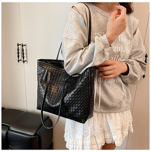 Detail of hand-woven black leather tote bag with Intrecciato pattern on model
