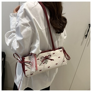 Detail view of white canvas shoulder bag with red bow, polka dots and lace trim