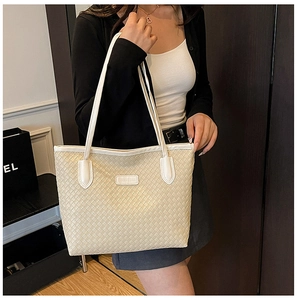 Detail of cream woven tote bag showing the Intrecciato pattern and fashion leather tag