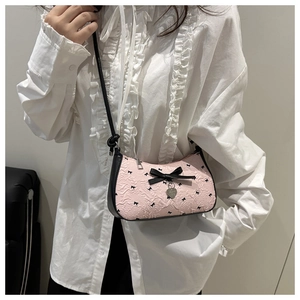 Détail du sac croissant rose avec motif nœud noir et pendentif en métal en forme de cœur