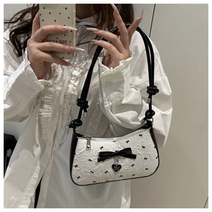 Détail du sac croissant gaufré blanc avec nœuds noirs et pendentif cœur argenté