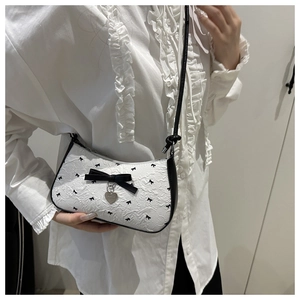 Détail du sac croissant avec nœuds noirs, motifs floraux et pendentif en forme de cœur argenté