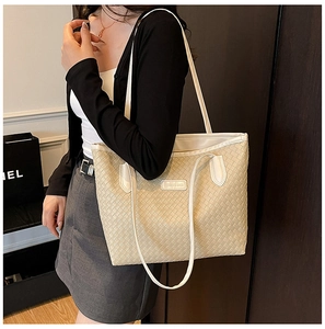 Detail of beige woven leather tote bag with thick interlaced texture and fashion label