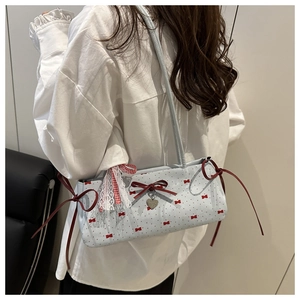Detailed close-up of light blue shoulder bag featuring red bows and lace ribbon accents