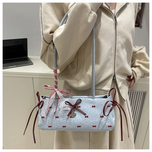 Detail of blue baguette bag with red bows, heart pendant, and gingham lace trim decoration