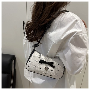 Détail du sac plissé blanc avec imprimés nœuds noirs et pendentif en forme de cœur