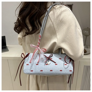 Detail of light blue polka dot shoulder bag with red ribbons and lace handle trim